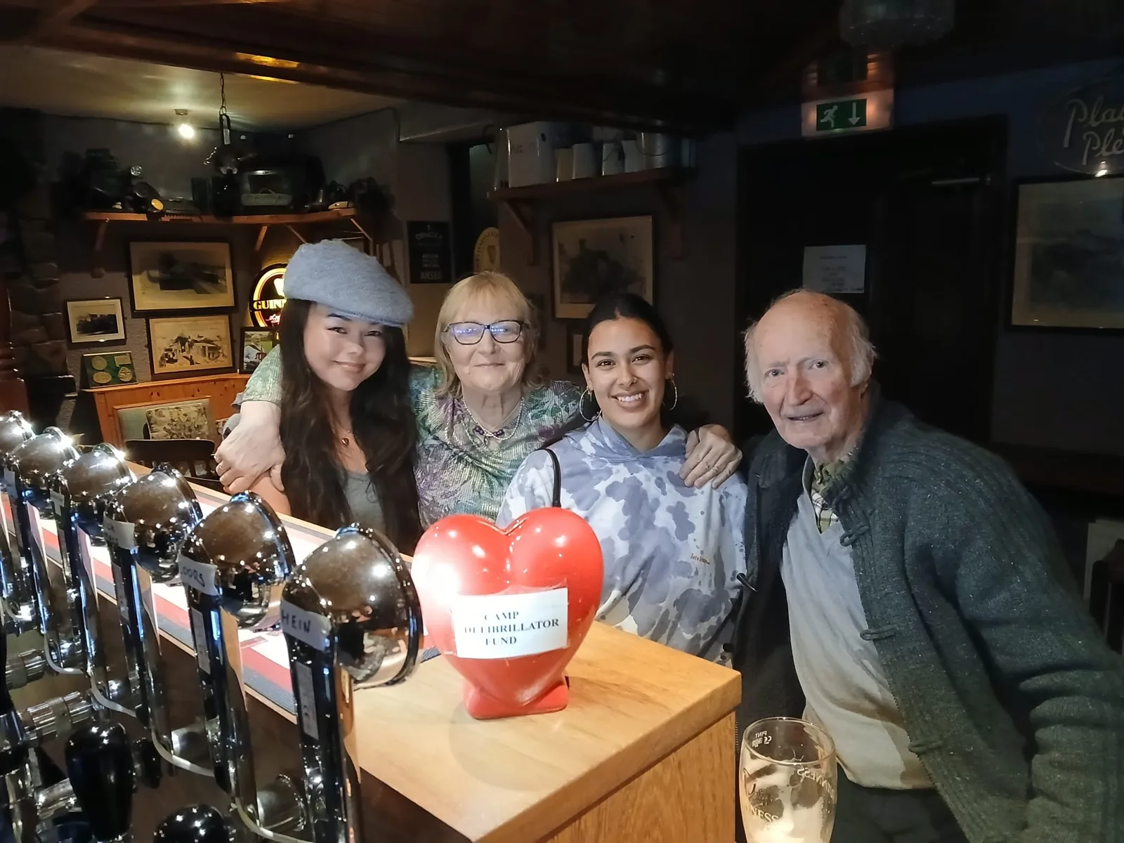 Four people gathered beside the counter in a pub