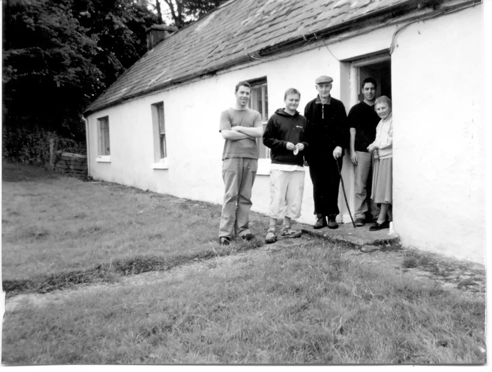 Black-and-white family photograph of five people outside a cottage