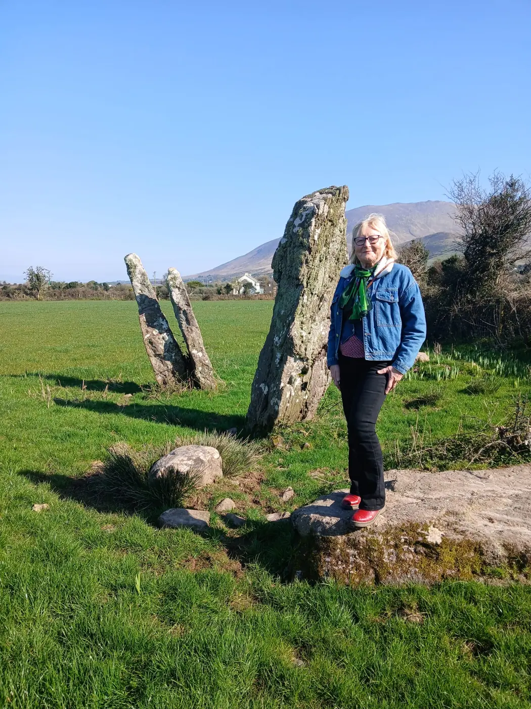 A visitor beside standing stones on the family farm in Gleann na nGealt